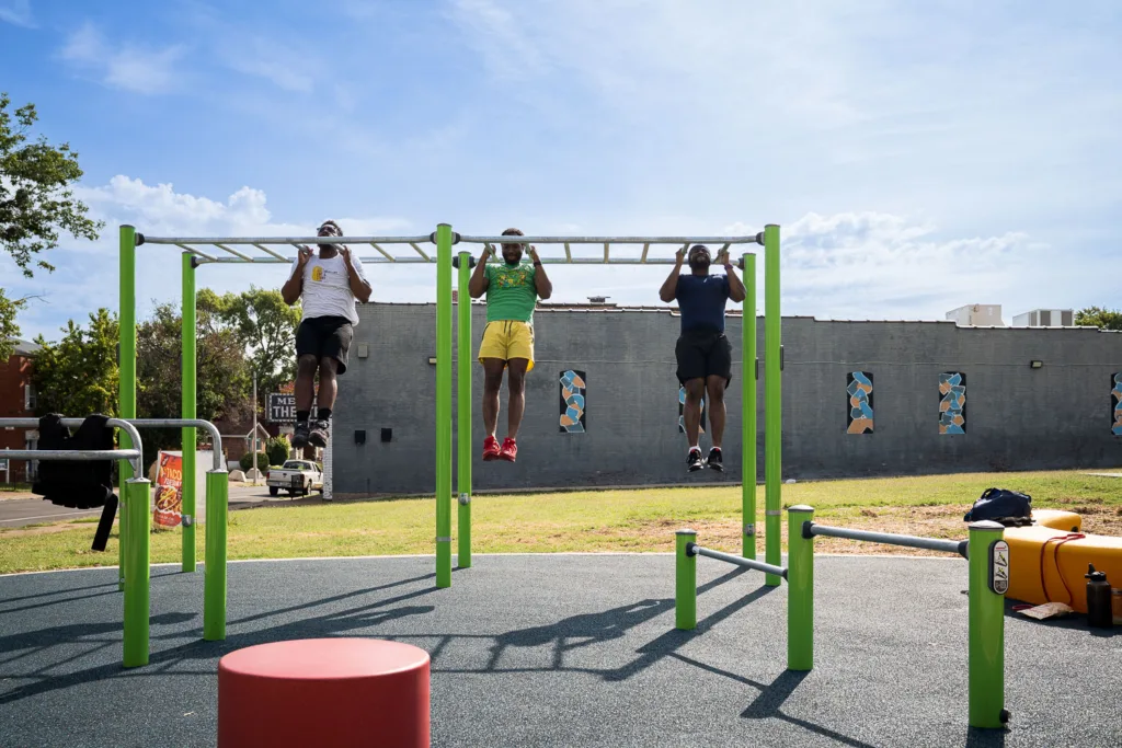 Three men do pull-ups.