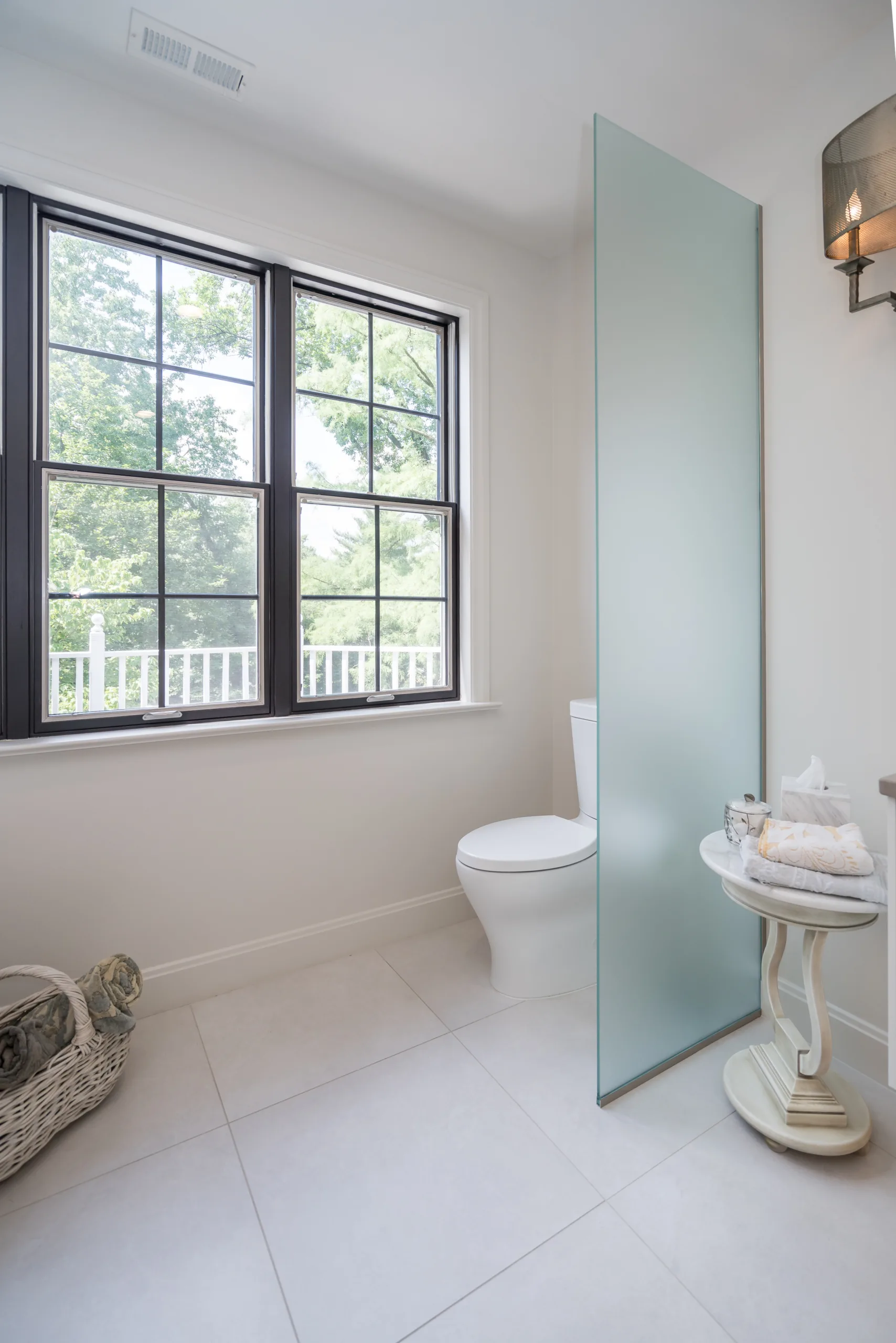 A frosted-glass privacy panel helps visually separate the toilet area without closing it off from the rest of the bathroom.