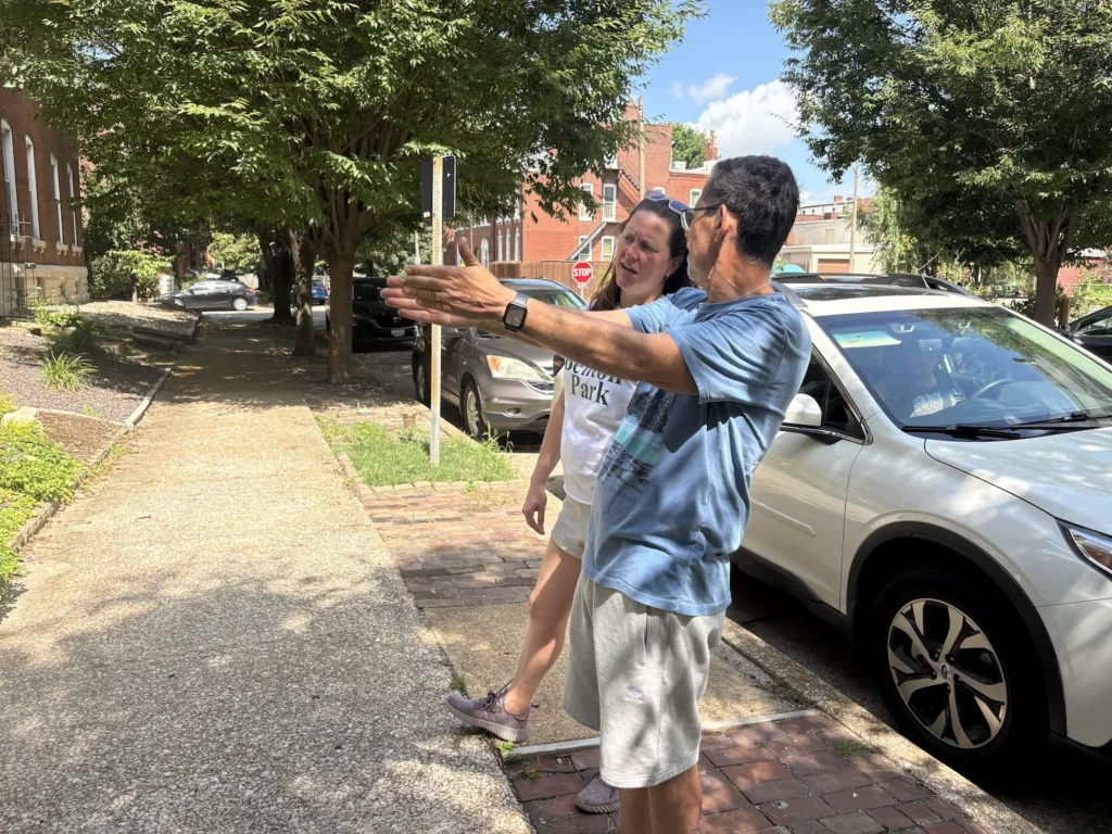 Two people gesture at a townhouse.