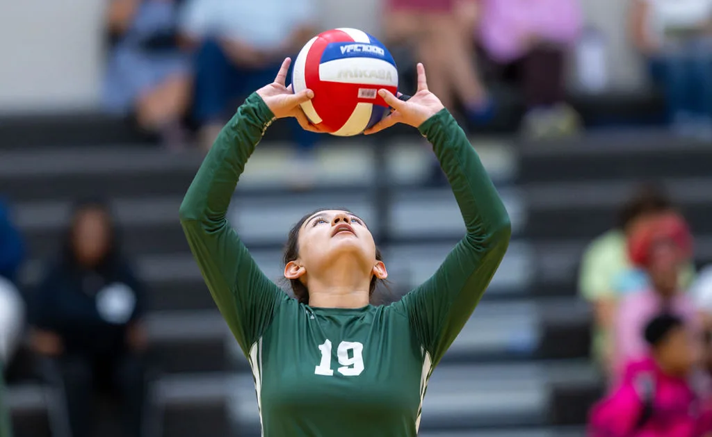 A Whitfield varsity volleyball player sets the ball during a match.