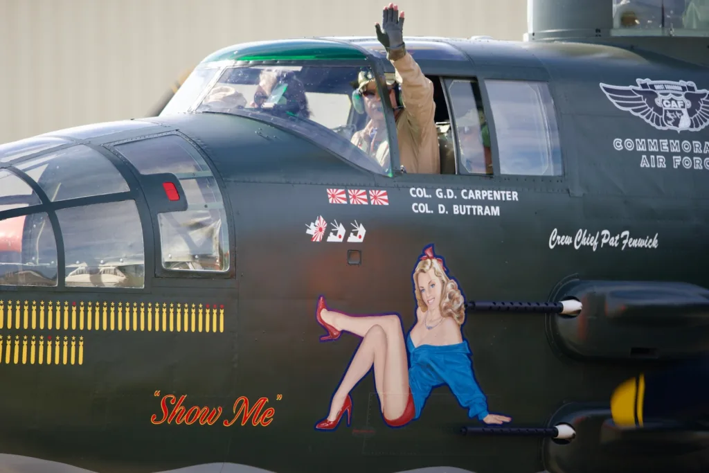 A man waves from the cockpit of a B-25.